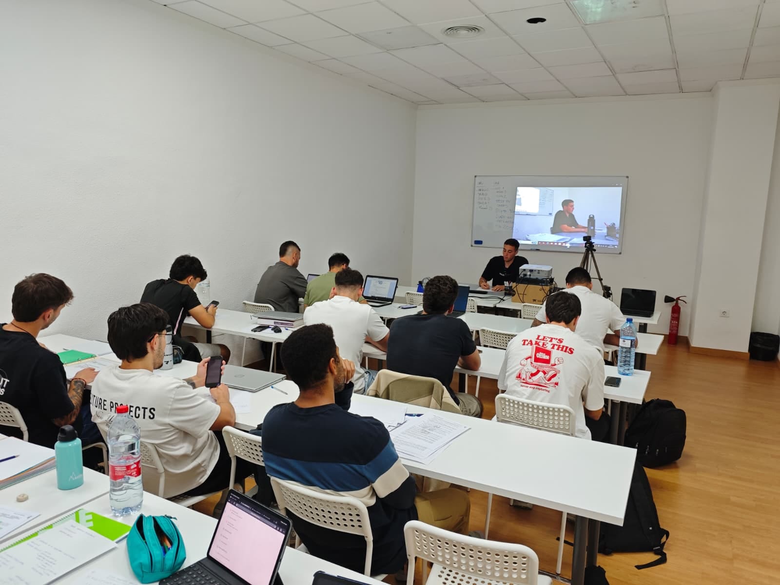 Alumnos en una clase presencial de Formación NEO, con la sesión seguida también en pantalla